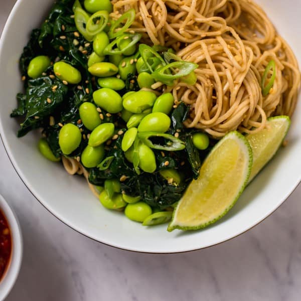 A cold Asian inspired soba noodle salad with garlic sauteed kale and edamame dressed in a creamy and gingery peanut sauce.
