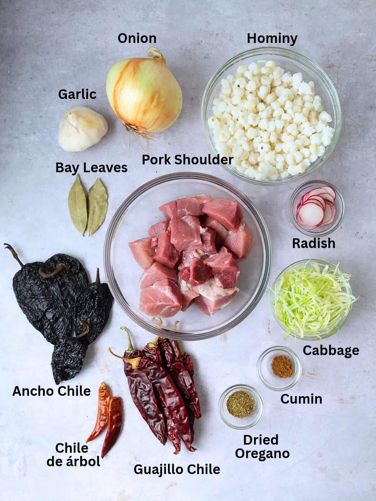 Ingredients for pozole rojo with dried chiles, dried oregano and cumin, hominy, pork shoulder and aromatics.