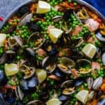 Seafood and chorizo paella is full of Pacific Northwest clams and mussels, wild salmon, spicy chorizo and garnished with sweet peas and bright lemon.