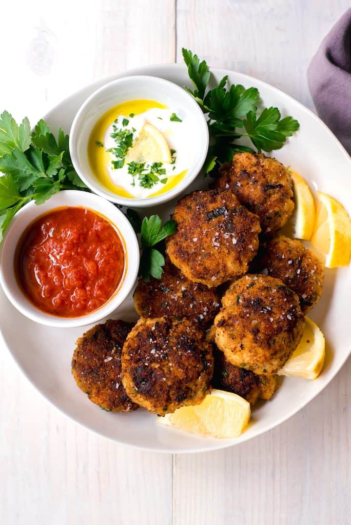 Mediterranean Fish Cakes full of bright lemon zest, garlic, leeks and spices and served along side smoky cumin tomato sauce and lemon horseradish to dip into.