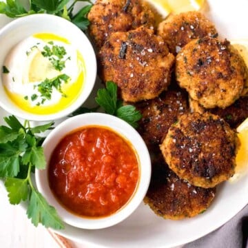 Mediterranean Fish Cakes full of bright lemon zest, garlic, leeks and spices and served along side smoky cumin tomato sauce and lemon horseradish to dip into.