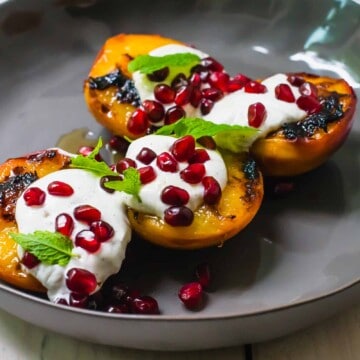 Simple summer dessert recipe, charred peaches with creamy and tangy labneh and topped with sweet honey and tart pomegranate seeds.