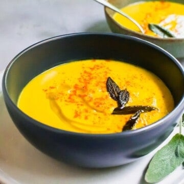 Thick and Creamy pumpkin soup with fresh roasted pumpkin is blended up with warm fall flavors of paprika and maple and topped with savory fried sage.