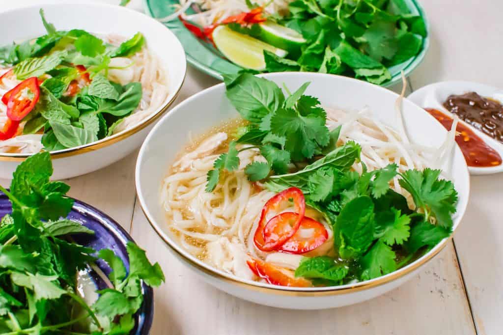 Veitnamese chicken pho aka pho ga is topped with thinly sliced chilis and fresh herbs.