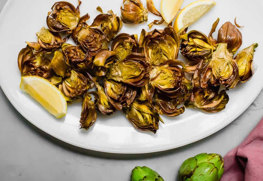 Roman style fried artichokes. Crispy baby fried artichokes fried in olive oil served with flakey salt and lemon juice. #FriedArtichokes #RomanFriedArtichokes