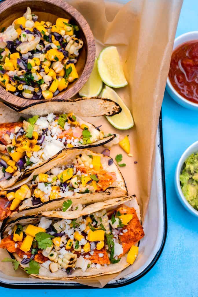 Get the grill going with sazon spiced salmon tacos, topped with a sweet and spicy colorful mango corn salsa for the perfect summer dinner.