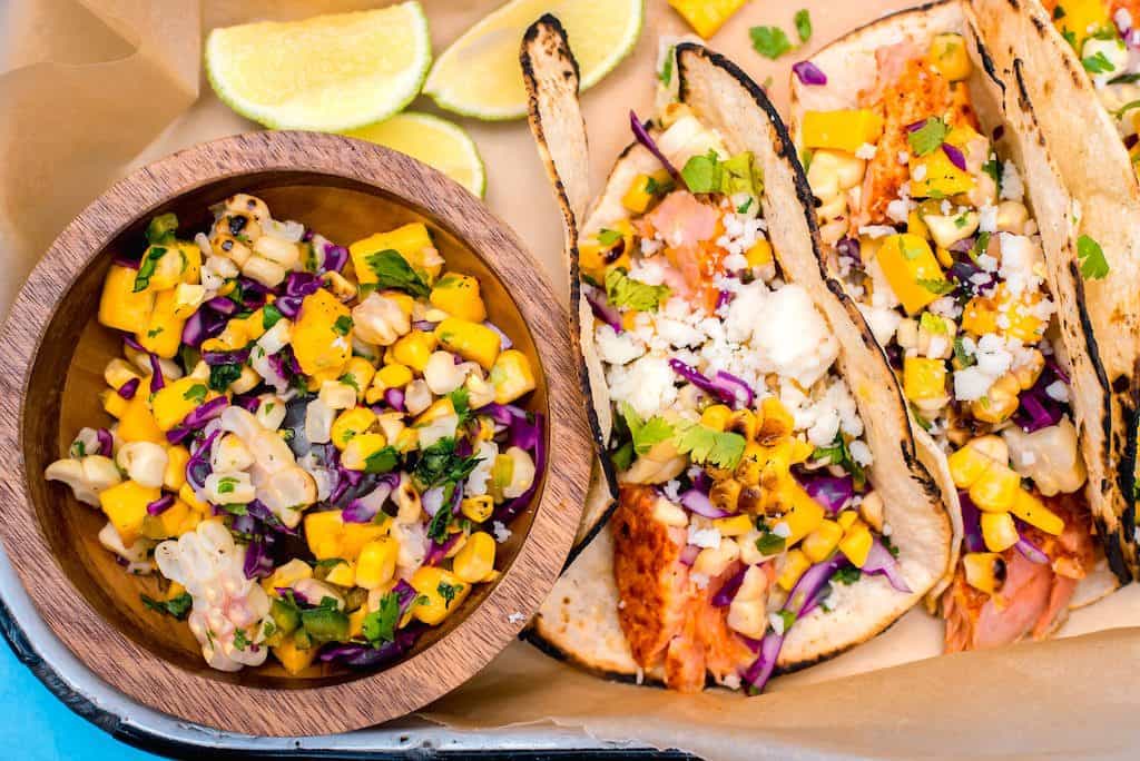 Get the grill going with sazon spiced salmon tacos, topped with a sweet and spicy colorful mango corn salsa for the perfect summer dinner.