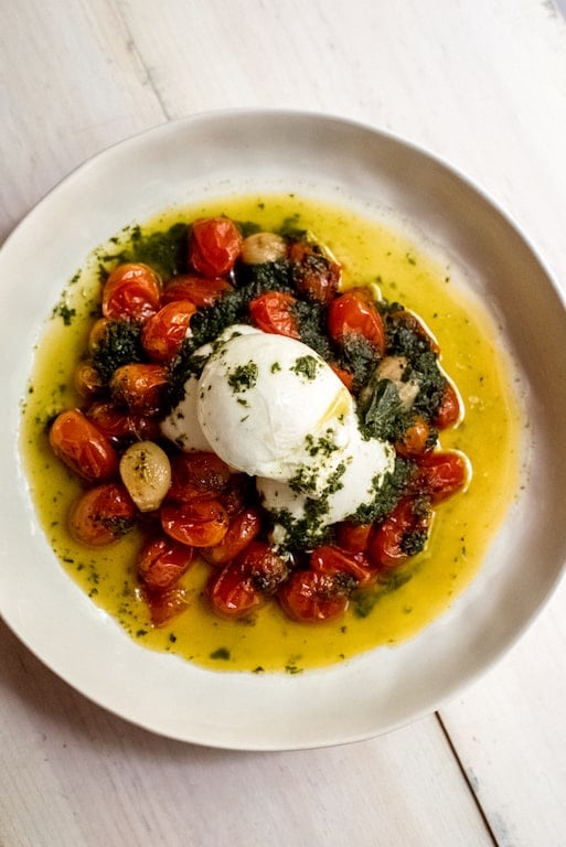 Slow roasted tomatoes are cooked with olive oil and garlic and served with a bright basil oil and creamy burrata. 