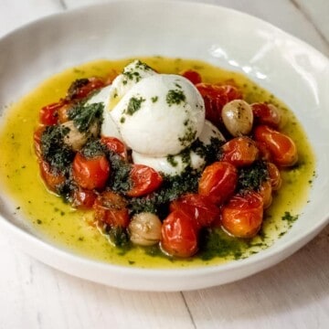 Slow roasted tomatoes are cooked with olive oil and garlic and served with a bright basil oil and creamy burrata.