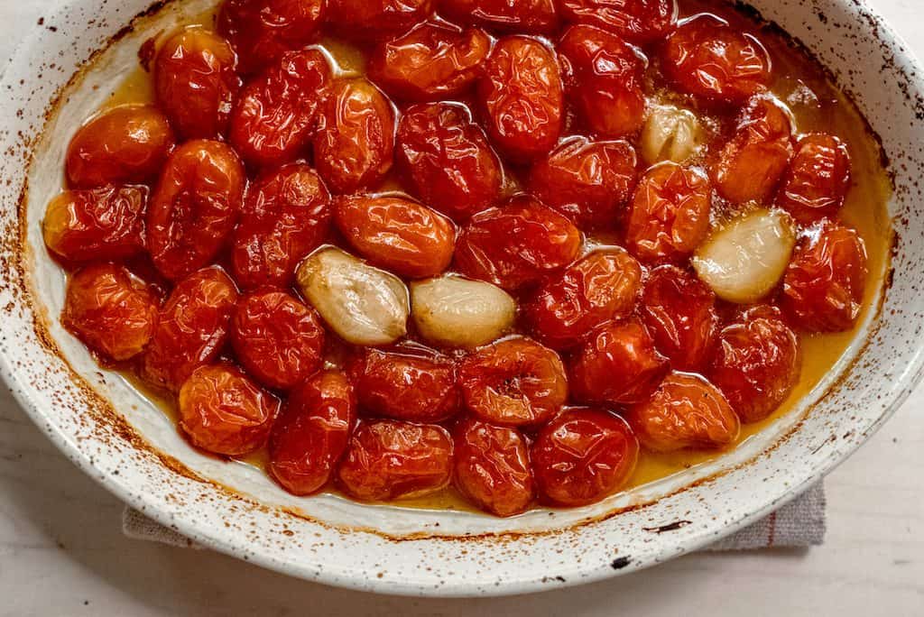 Sweet cherry tomatoes are slow roasted with olive oil and whole garlic cloves until softened and slightly charred.