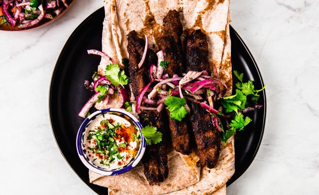 Kofta Kebabs are a popular and flavorful Mediterranean street food. Ground beef and lamb are flavored with aromatic spices and fresh herbs and pressed onto skewers before being grilled over charcoal. Serve with creamy tahini sauce and sumac onion salad. 
