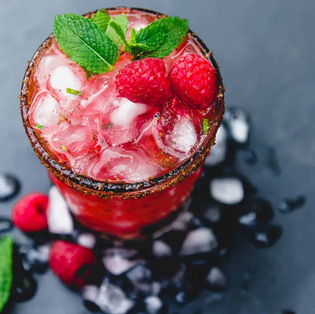Smoky, slightly sweet and a bit tart, this  refreshing mezcal cocktail is muddled with fresh raspberries and mint and garnished with a Tajin rim.