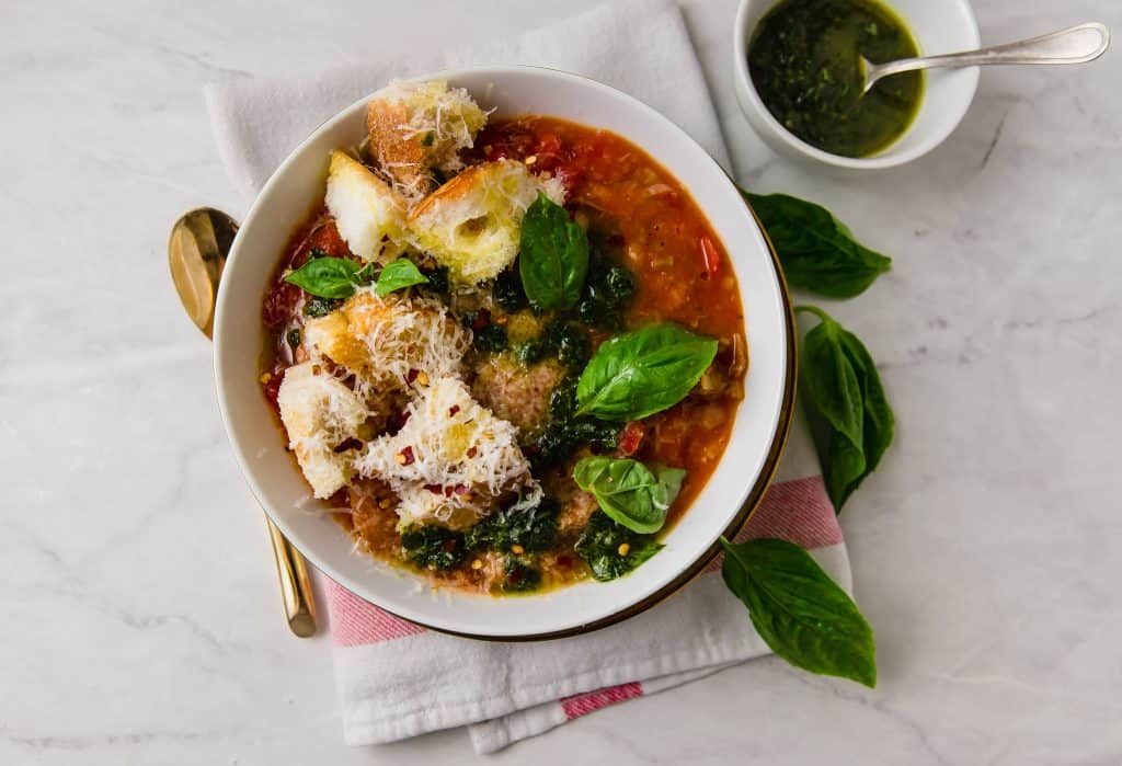 Tuscan bread soup also called ribollita is a hardy vegetarian soup thickened by day old bread, sweet tomatoes and finished with a bright basil oil and a good grate of Parmigiano Reggiano.