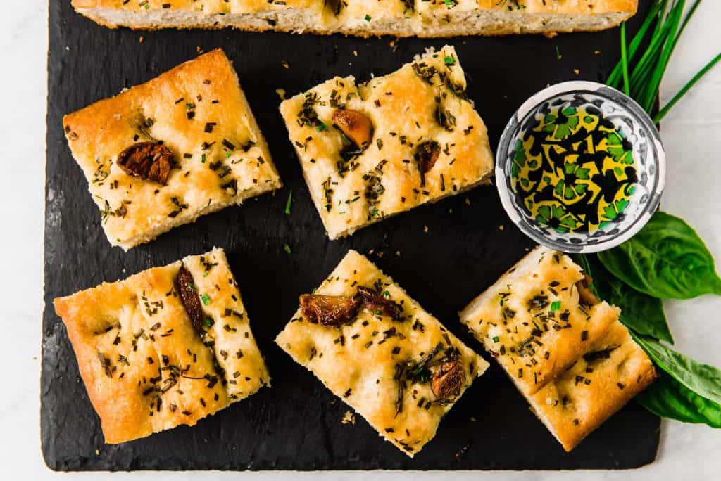 Savory and sweet roasted garlic is nestled into airy focaccia and topped with garlic oil, loads of fresh herbs and flaky sea salt. 