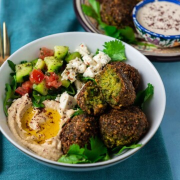 Fried falafel balls served in a bowl with chopped salad and hummus.
