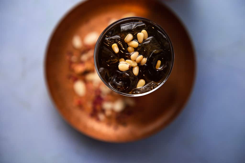 A floral and refreshing Middle Eastern drink inspired from Lebanon, Jallab is made with date molasses, a touch of rose mater and topped with pine nuts.