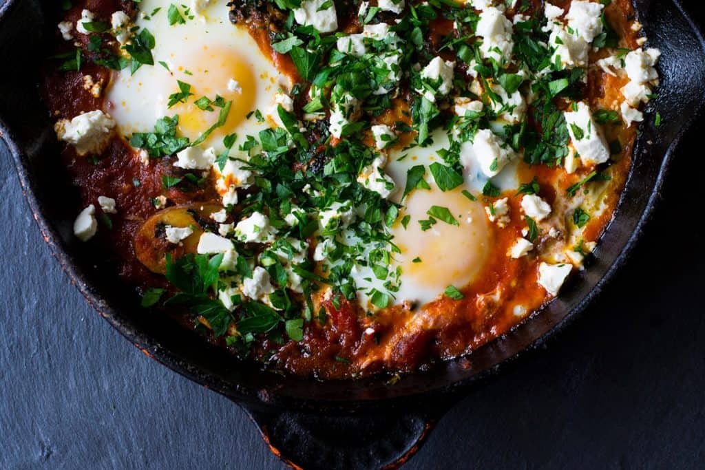 A hearty and smoky vegetarian shakshuka recipe loaded with sauteed kale, mushrooms and peppers. The tomato is seasoned with deep spices of cumin and paprika and once the dish is just done cooking, everything is topped with creamy feta and lots of fresh herbs. 