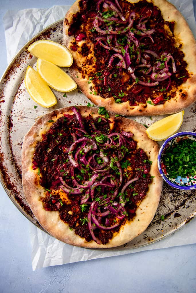 Vegan Turkish pizza AKA lahmacun is a thin crust pizza flavored with a bold and tangy vegetable mixture and topped with red onions and sumac.