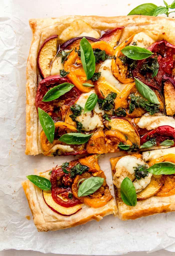 Peach caprese tart with heirloom tomatoes, mozzarella and peaches layered on top of buttery puff pastry and finished with basil and balsamic.
