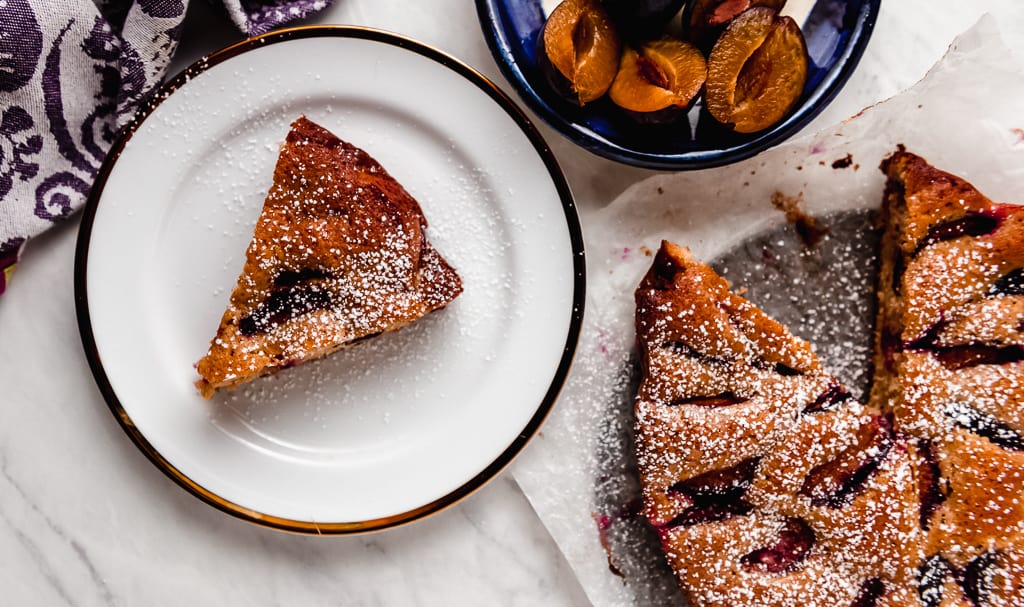 Simple and sweet plum cake recipe flavored with warm cinnamon, vanilla and finished with a light dusting of powdered sugar. 