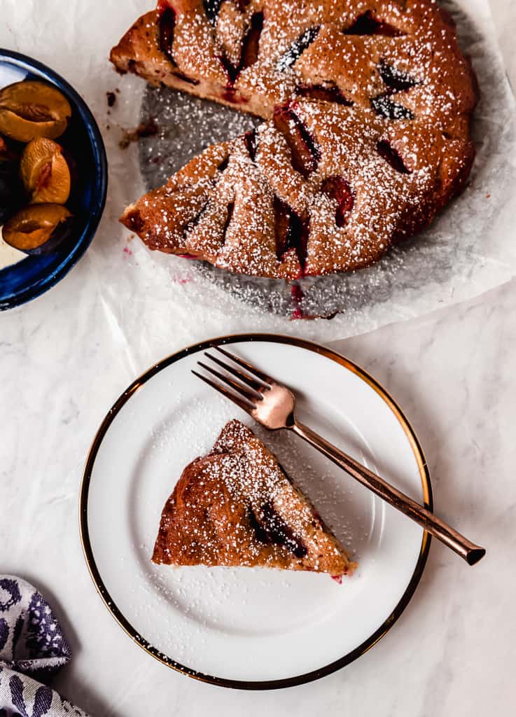 Simple and sweet plum cake recipe flavored with warm cinnamon, vanilla and finished with a light dusting of powdered sugar.