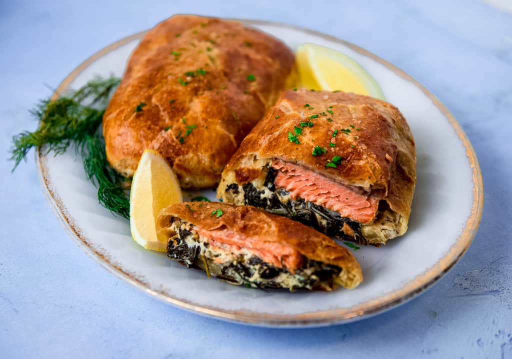 Salmon wellington is a filet of salmon, layered with a creamy spinach mixture and wrapped in puff pastry. The salmon wellington is baked until perfectly golden brown.