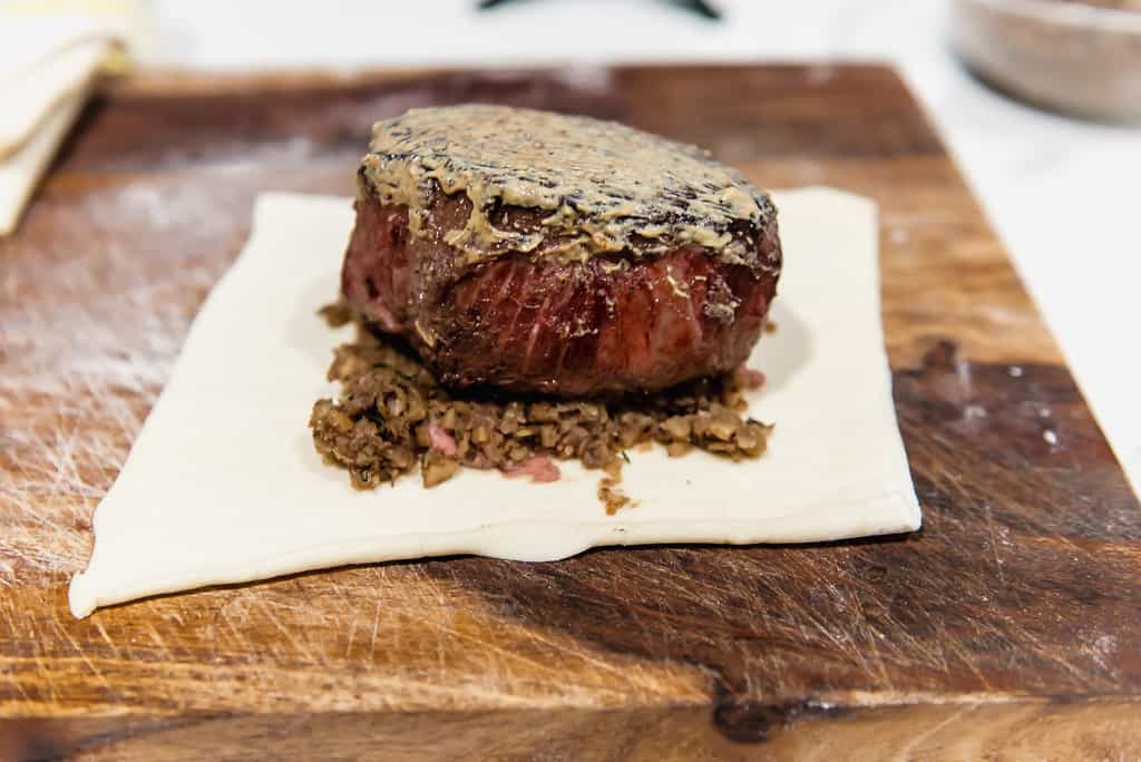 3. Layer filet with mushroom and chestnut duxelle and spread a layer of Dijon mustard on the steak.
