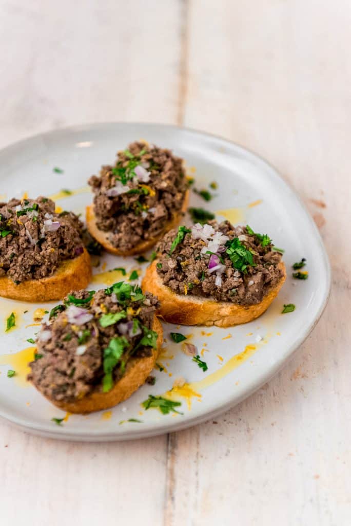 This flavorful chicken liver paté is chopped coarsely and showcases bright Mediterranean flavors of capers, fresh herbs and a good amount of lemon zest. 