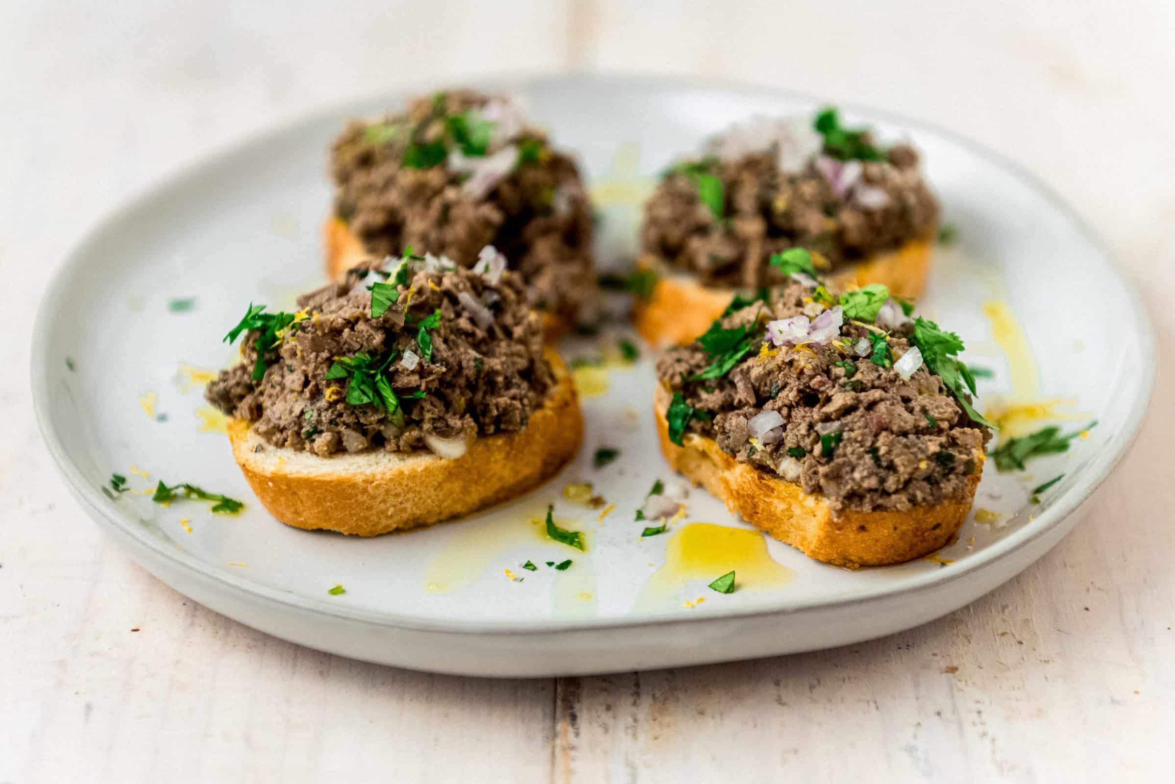 This flavorful chicken liver paté is chopped coarsely and showcases bright Mediterranean flavors of capers, fresh herbs and a good amount of lemon zest. 