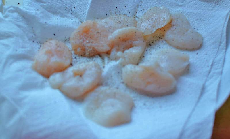Dry scallops with a paper towel and slice them in half. Season with salt and pepper and right before you're ready to saute, dust in flour, removing any excess.