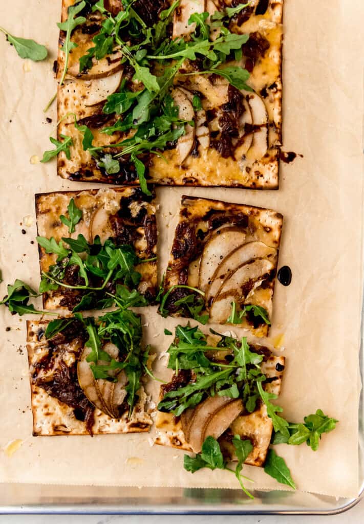 Savory matzo pizza is topped with melty brie cheese, caramelized onions and sweet pears. It doesn't get any better than this!