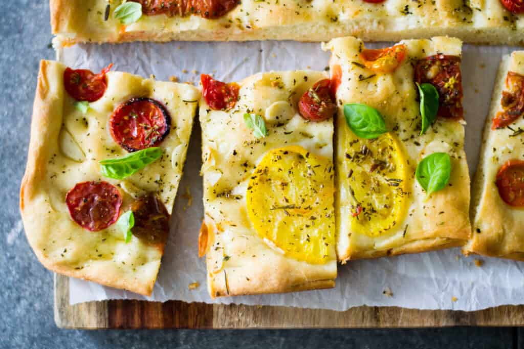 Heirloom tomato and garlic focaccia has slices of tomatoes and garlic nestled into savory focaccia bread with loads of fresh herbs.