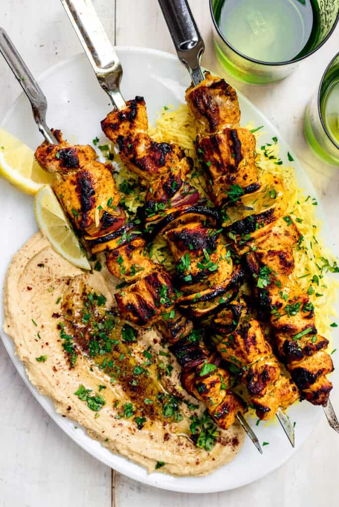 Grilled chicken shawarma skewers are seasoned with a stunning mix of Mediterranean spices, garlic, lemon and grilled to perfection. The kebabs are served alongside hummus and saffron rice.