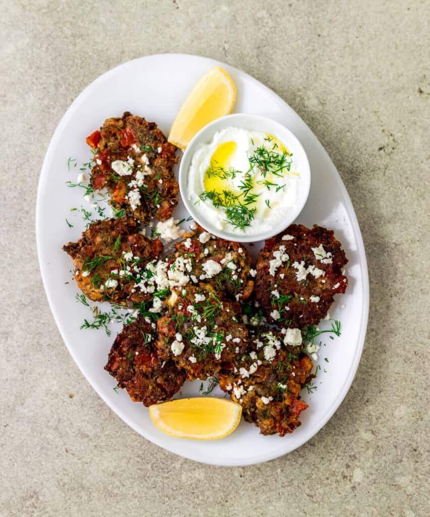 Greek tomato fritters are savory pancakes that are full of sweet tomatoes, fresh mint, dill and creamy feta cheese. The tomato fritters is fried until perfectly golden brown on both sides and served with a bright and lemony yogurt dill sauce. 