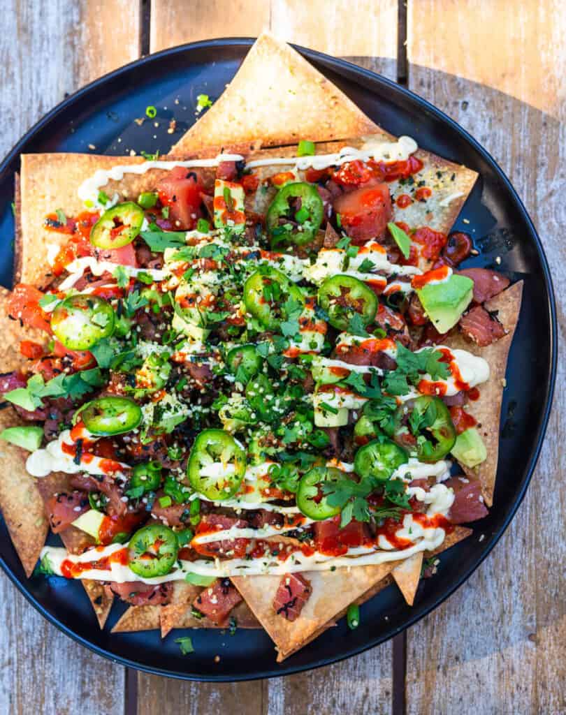 Poke nachos is a fun twist of cultural flavors. Seasoned Ahi poke is layered onto of baked wonton chips and garnished with a drizzle of sriracha, Japanese mayo, cubed avocado, fresh cilantro leaves and thinly sliced jalapeno.
