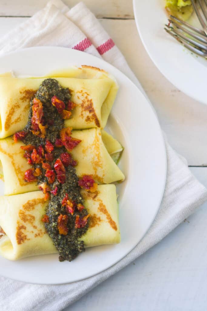 Savory blintzes are stuffed with shredded mozzarella and sundried tomatoes and once rolled up, are topped with pesto and more sundried tomatoes. 