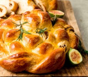 Sweet dried figs, cinnamon and honey cook down together and are spread onto strands of this round fig challah. Once baked and cut unto, the dried fruit mixture peeks out into beautiful swirls.