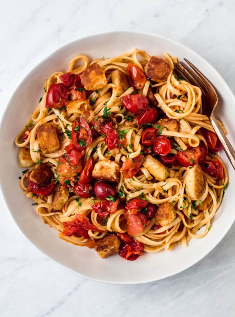 This easy halloumi pasta has a simple sauce of garlic and burst cherry tomatoes and grated Parmesan cheese. Cubes of fried halloumi cheese is added right on top of the pasta. 