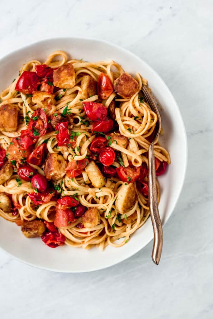 Long noodles of pasta is cooked with burst cherry tomatoes, garlic and Parmesan cheese and topped with cubes of perfectly fried halloumi. 