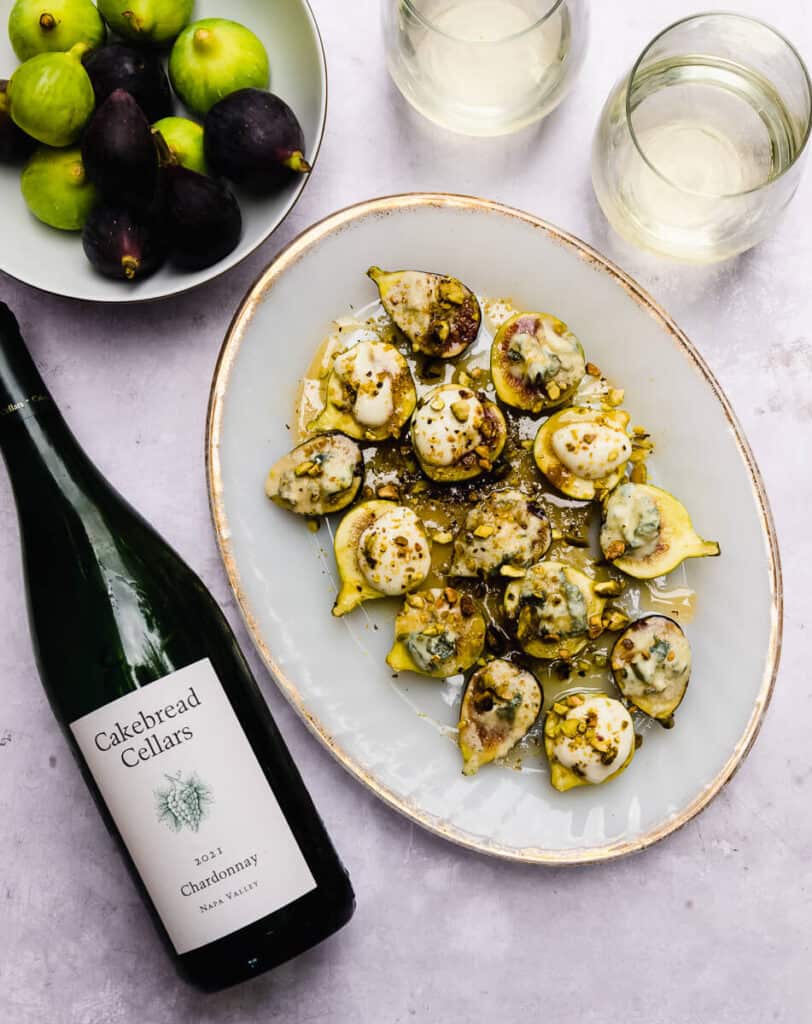 Baked figs with pistachios and honey is paired with a Chardonnay wine. The fresh figs are baked with dollops of blue cheese and some with whipped goat cheese.