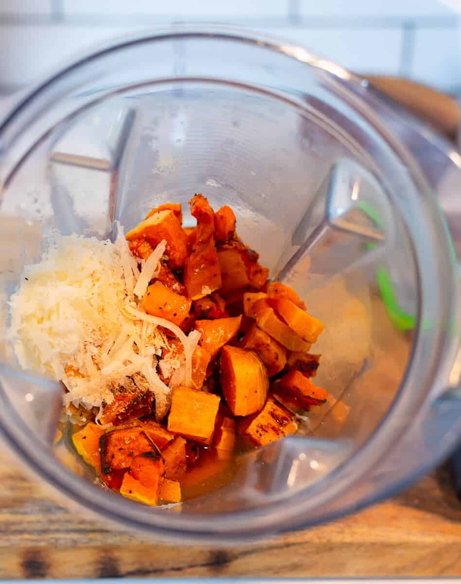 For a smooth butternut squash pasta sauce, add the roasted butternut squash, roasted garlic cloves, grated Parmesan cheese and nutmeg to a blender.