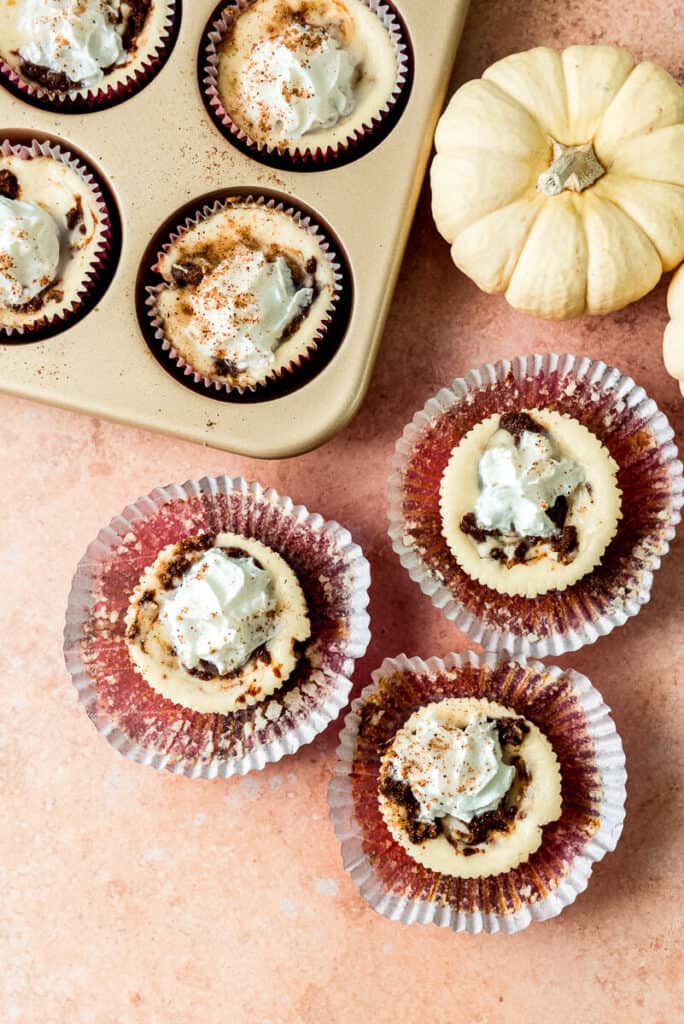 Mini cheesecakes are served in cupcake lines and made in a muffin tin. These individual cheesecakes are swirled with spiced pumpkin and topped with whipped cream and a dusting of grated nutmeg. 