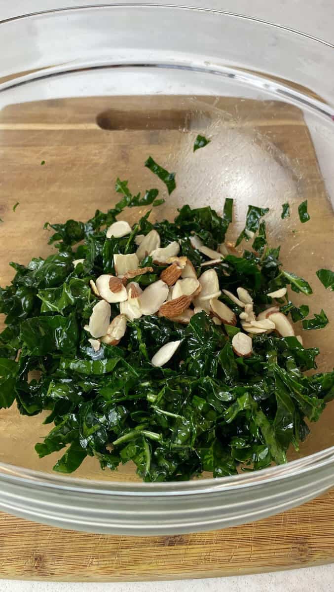 Add the sliced almonds to the shredded kale in a large bowl.