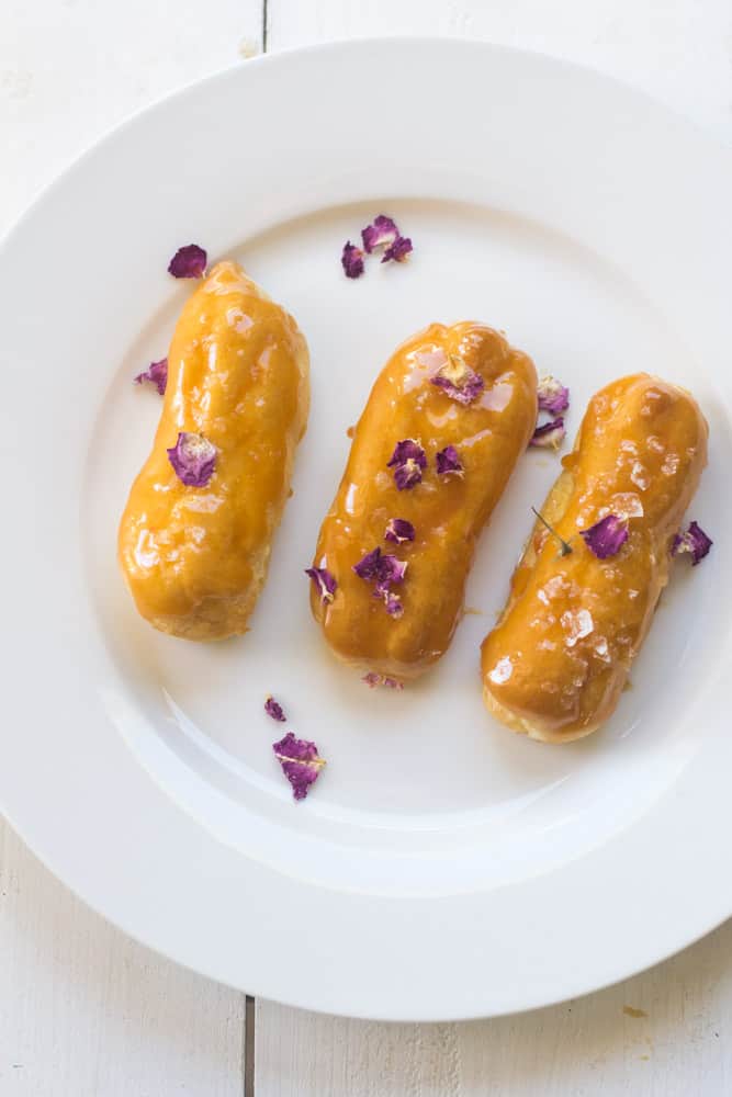 Salted caramel eclairs are garnished with rose petals for color.