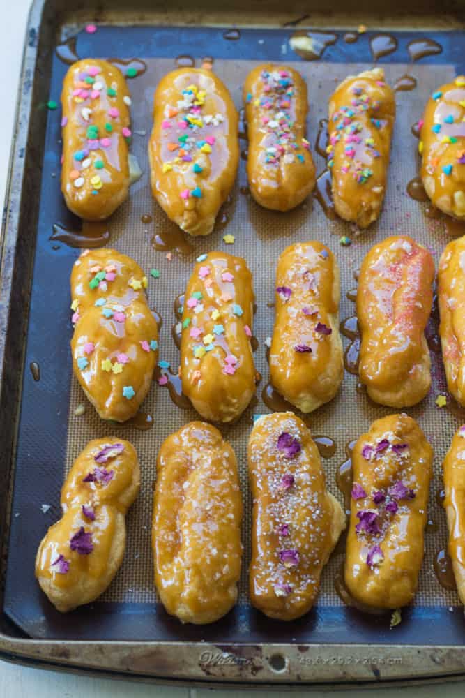 Assembled caramel eclairs decorated with edible sprinkles.