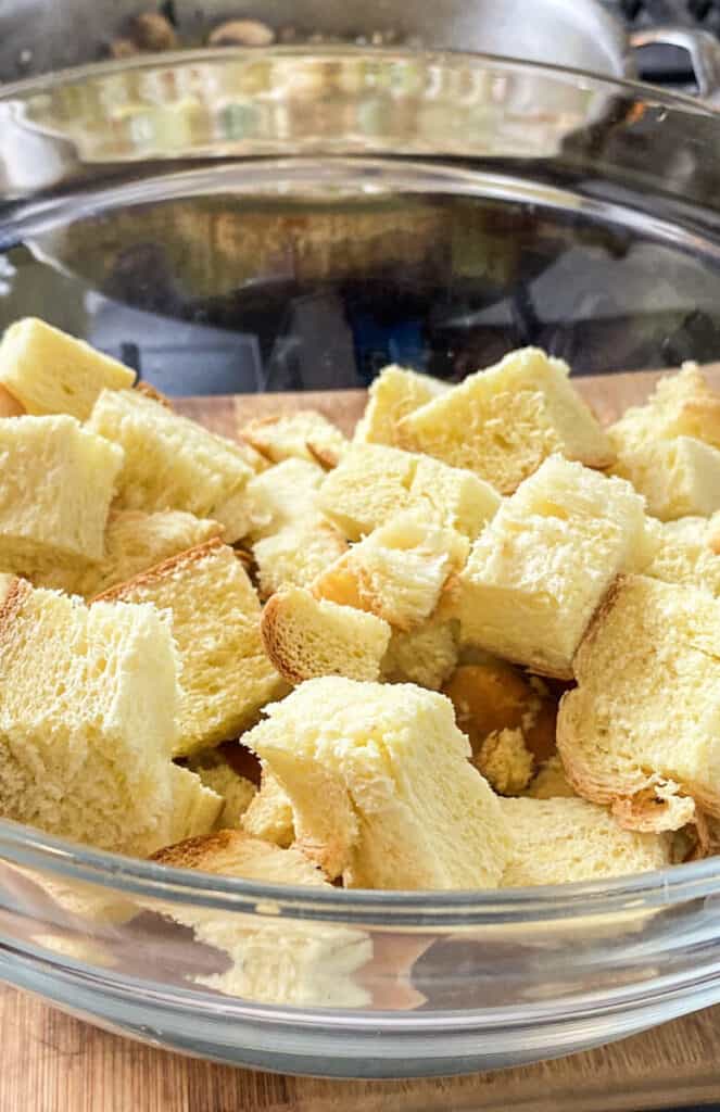 Add cubed challah bread to a large bowl before adding the vegetable mixture.