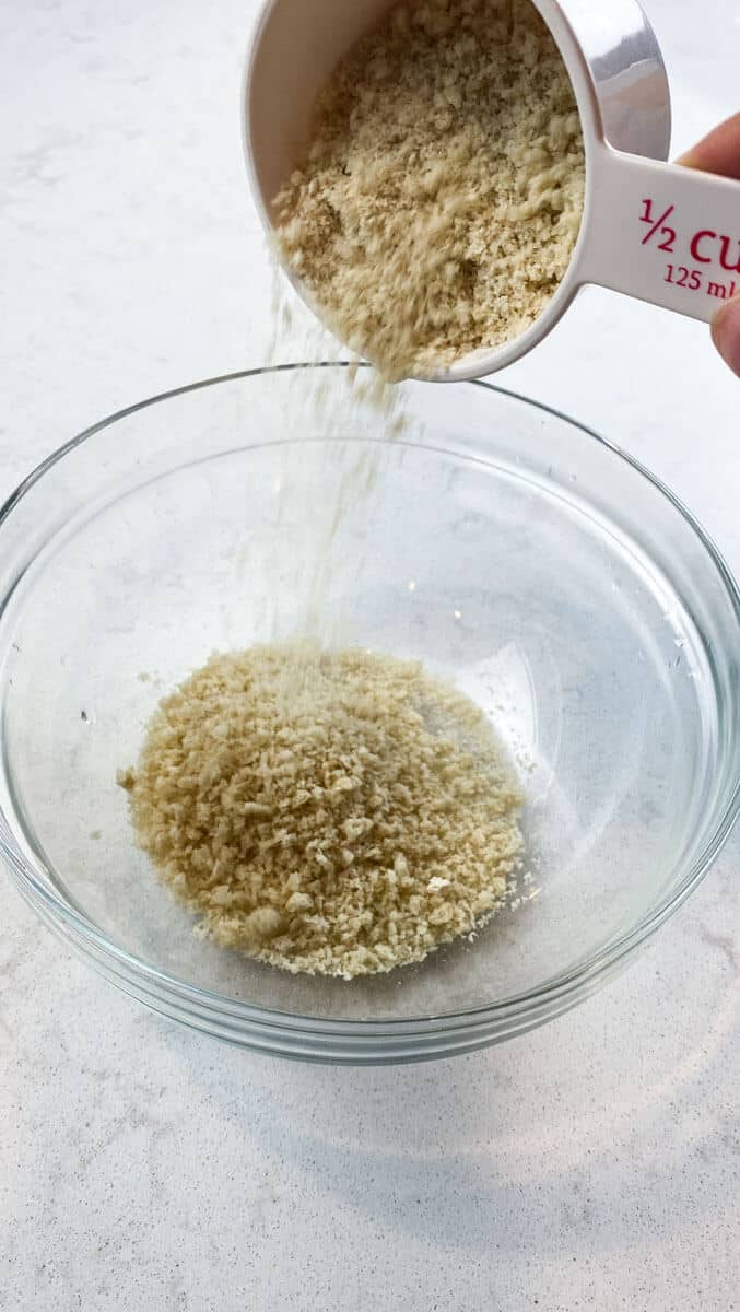 Panko breadcrumbs being poured into a bowl to add to roasted delicata squash.