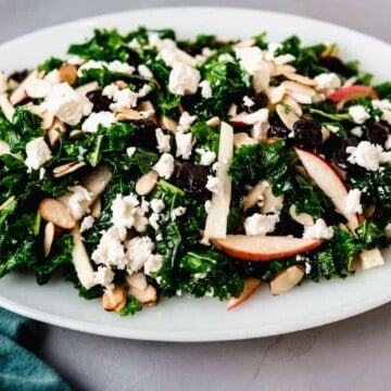 Serve the kale cranberry salad on a platter with crumbled feta cheese and apples.