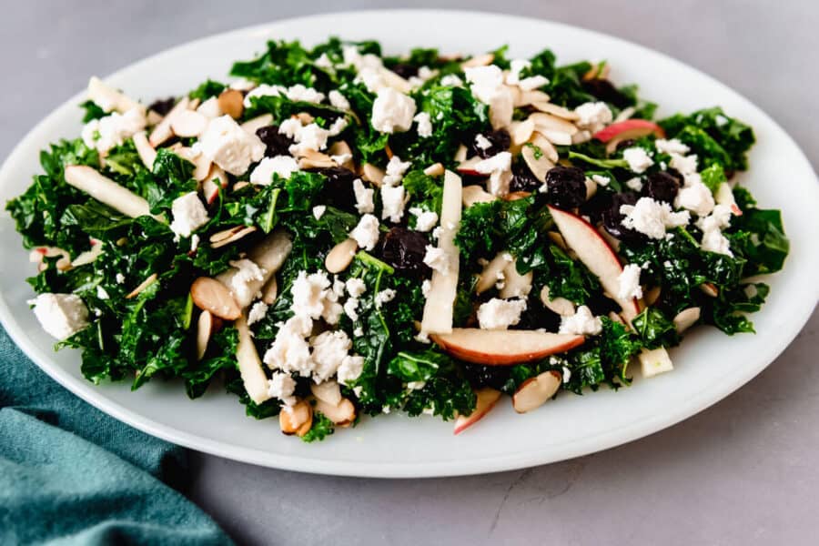 Serve the kale cranberry salad on a platter with crumbled feta cheese and apples.