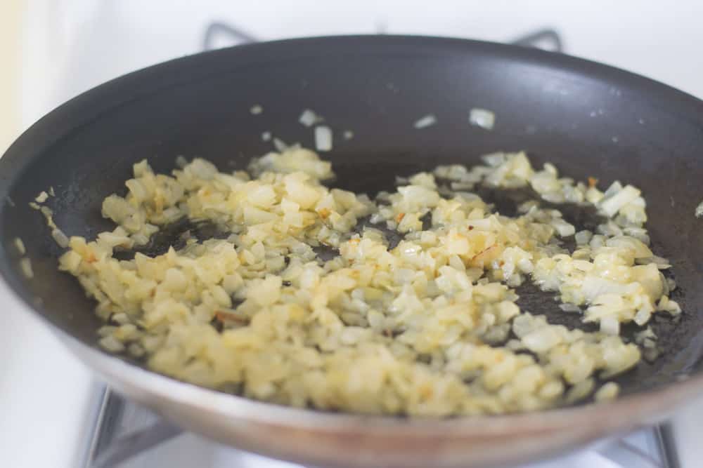 The beginning of sautéing chopped onions in a skillet.